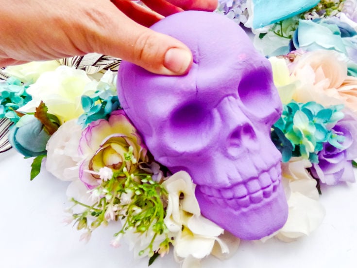 attaching pastel painted skull to dollar store diy halloween wreath